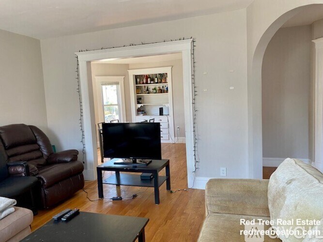 A living room with a brown leather couch, a black coffee table, and a television.