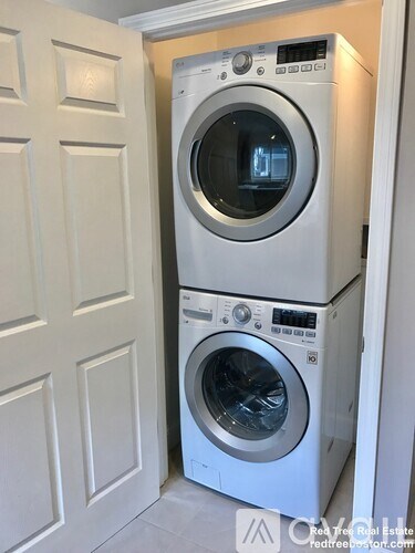 Two washing machines stacked on top of each other in a small space.