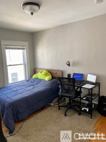 A bedroom with a bed, desk, and chair.