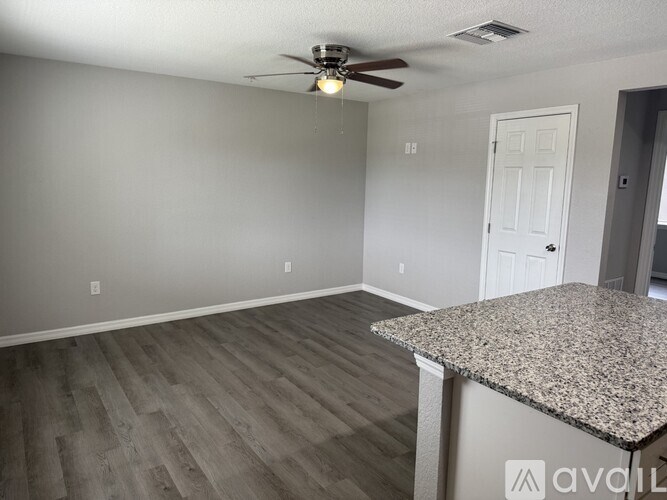 A room with a ceiling fan and a door.