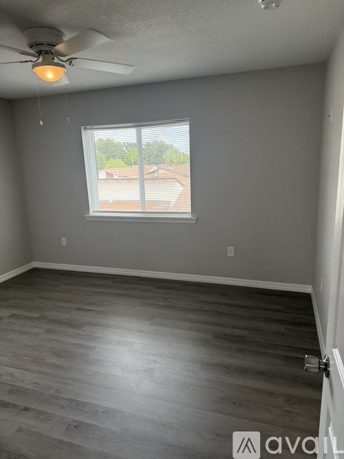 A room with a ceiling fan and a window overlooking a backyard.