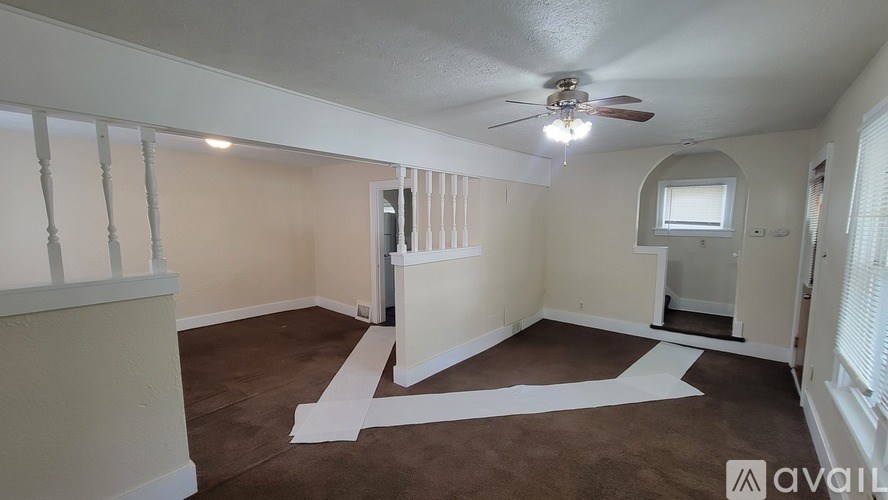 A room with a fan on the ceiling and a window with blinds.
