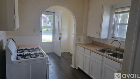 A kitchen with a stove, sink and cabinets.