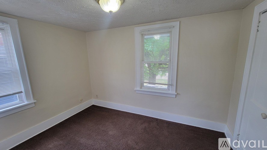 A room with a window and a brown carpet.