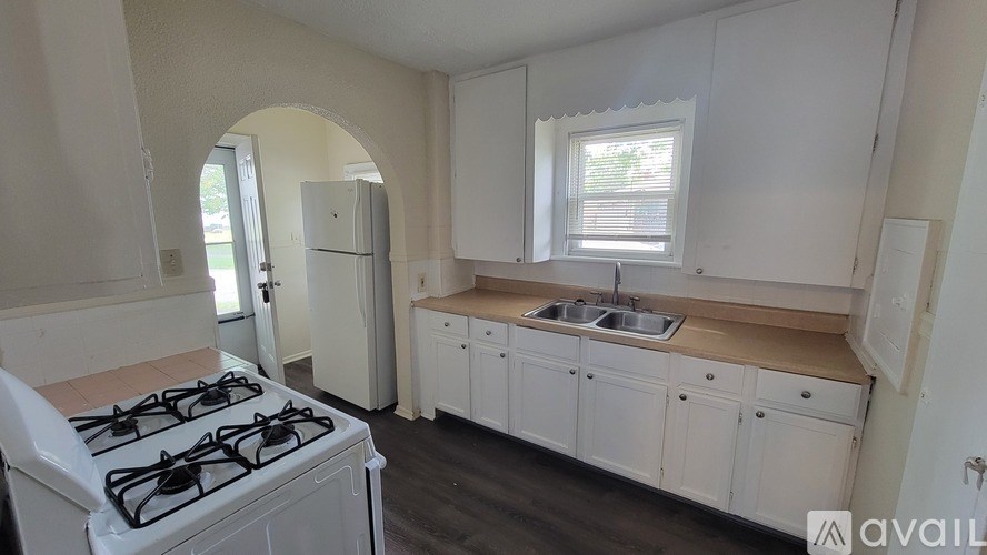 A kitchen with a white gas stove and white cabinets.