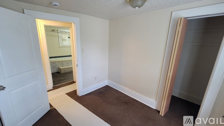 A room with a white door and a brown carpet.