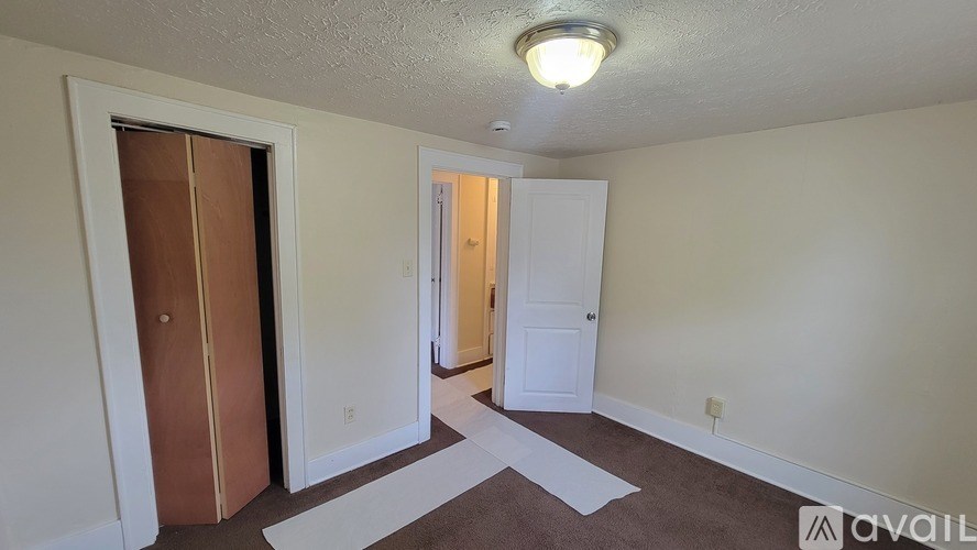 A room with a brown door and a white door with a carpet on the floor.