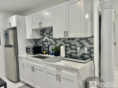 A kitchen with white cabinets and a black and white tiled backsplash.