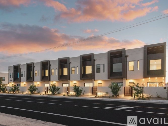 A modern building with a row of windows and doors is illuminated by lights.