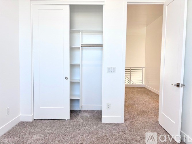 A white door is open to a hallway with a white wall.