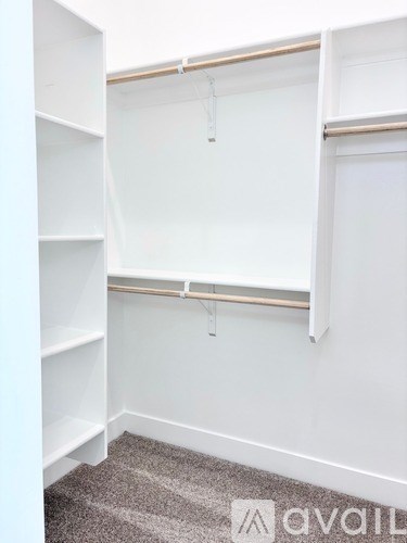 A white closet with a carpeted floor and a hanging rod.