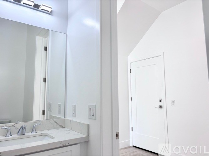 A bathroom with a sink, mirror, and a door.