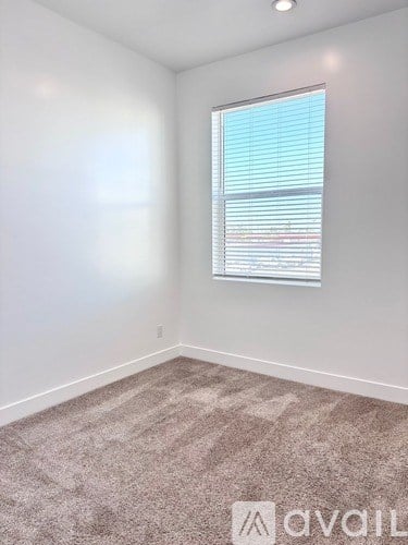 A room with a carpeted floor and a window with blinds.