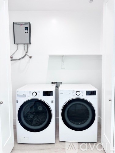 Two white front loading washing machines in a small laundry room.