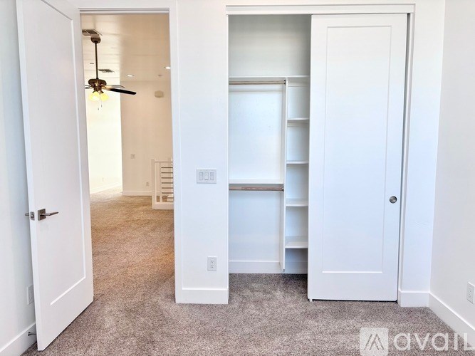 A white door is open to a room with a ceiling fan.