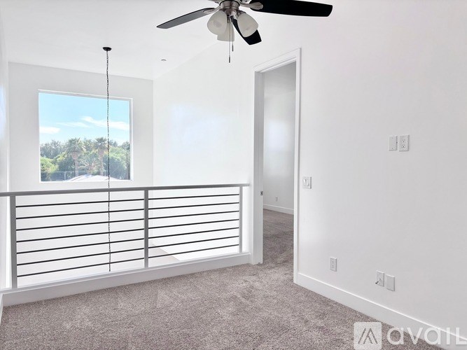 A room with a ceiling fan and a window overlooking a landscape.