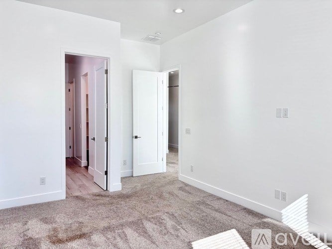 A carpeted room with a white door and a white wall.