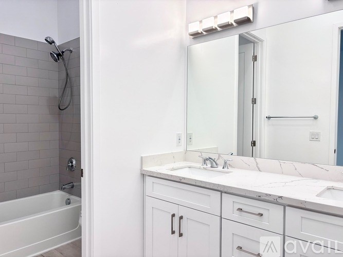 A white bathroom with a tub, sink, and mirror.