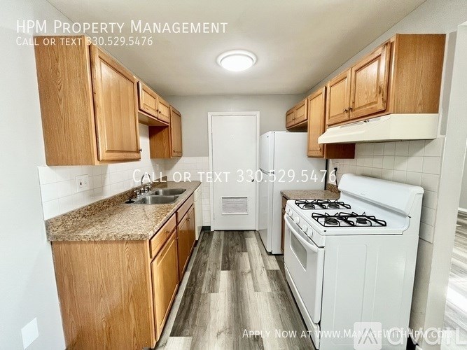 A kitchen with wooden cabinets and a white stove top oven.