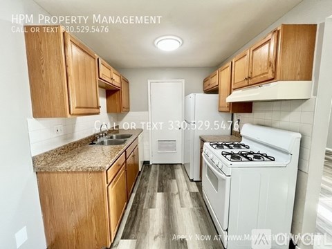 A kitchen with wooden cabinets and a white stove top oven.