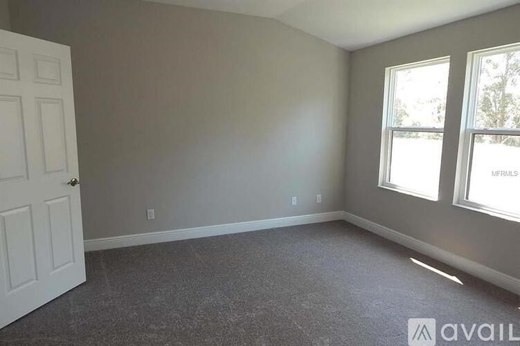 A room with a carpeted floor, a door, and a window.