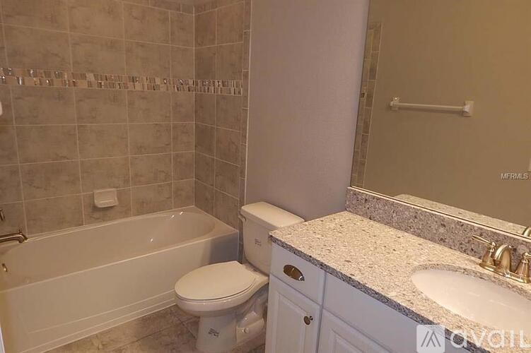 A bathroom with a white toilet, a white bathtub, and a marble countertop.