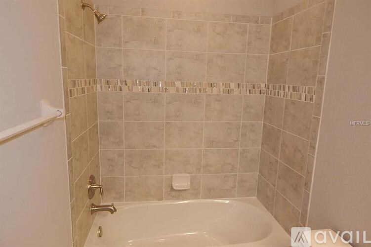 A bathroom with a white tub and tiled walls.