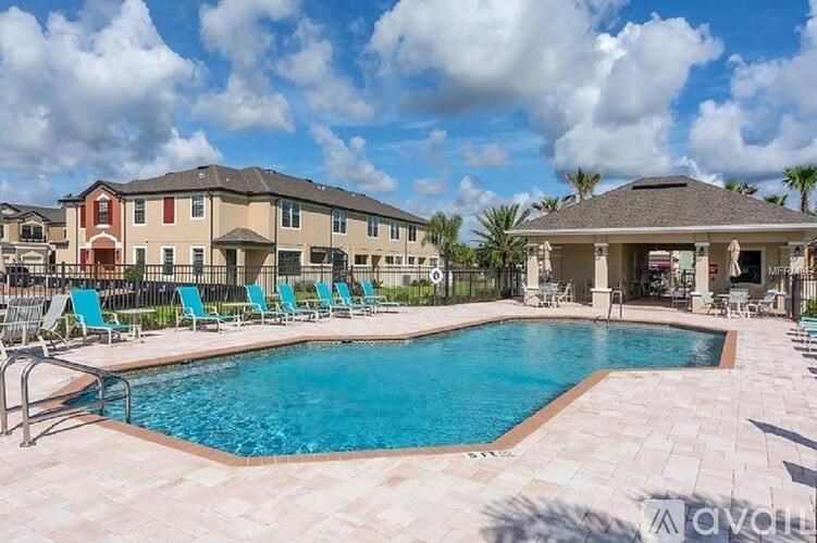A large swimming pool surrounded by lounge chairs in front of apartment buildings.