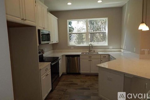 A kitchen with white cabinets and a window.