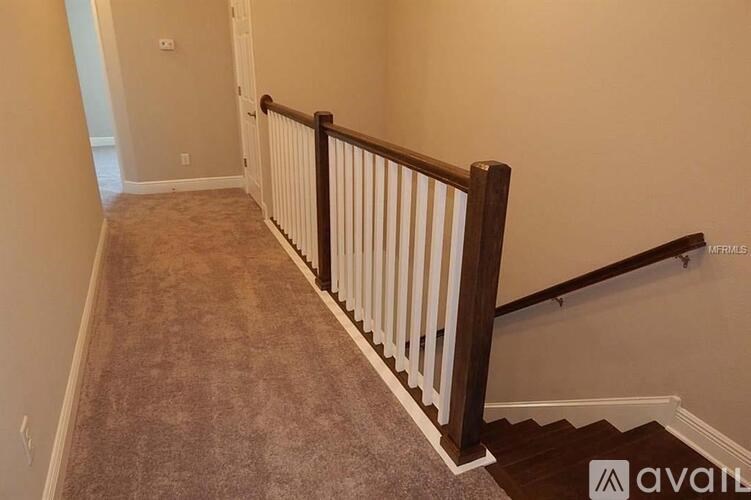 A hallway with a carpeted floor and a wooden railing.