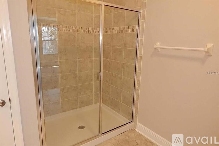 A bathroom with a glass shower door and a white towel bar.