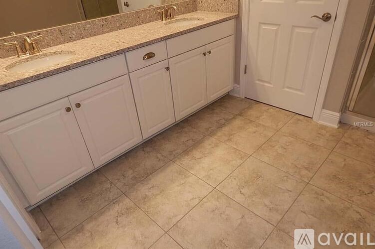 A bathroom with a tiled floor and white cabinets.