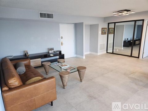 A living room with a brown leather couch and a glass coffee table.