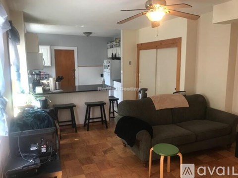 A living room with a grey couch and a green stool.