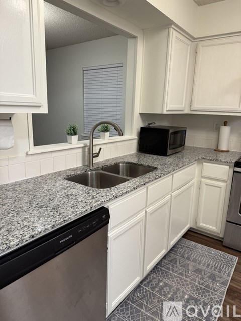 A kitchen with white cabinets and granite countertops.