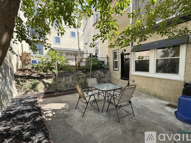 A patio with a table and chairs is surrounded by trees.