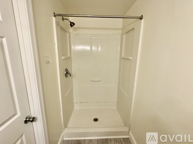 A white bathroom with a walk-in shower and a door.