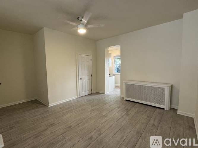 A room with a wooden floor and a white ceiling fan.