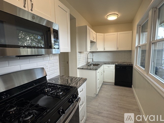 A kitchen with a black stove top oven and white cabinets.