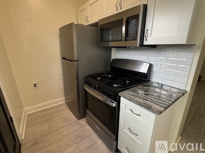 A kitchen with a stainless steel refrigerator, microwave, and black stove top oven.