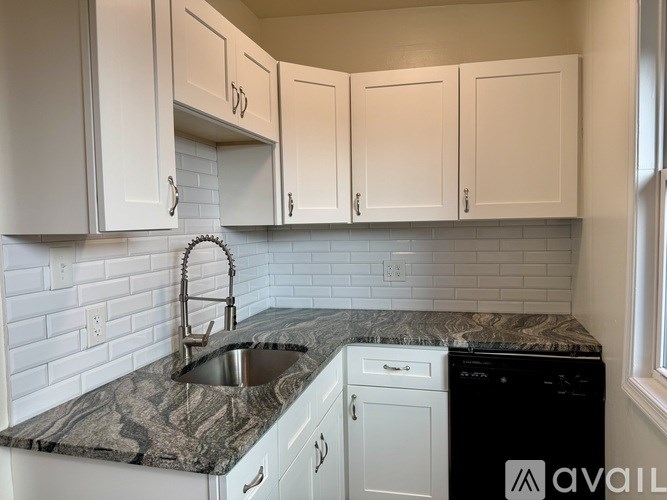 A kitchen with white cabinets and a marble countertop.