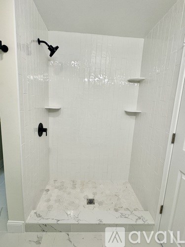 A white tiled bathroom with a marble floor.