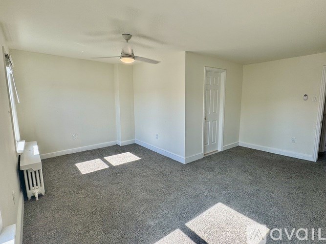 A room with a ceiling fan and carpeted floor.