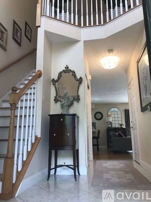 A hallway with a mirror and a wooden staircase.