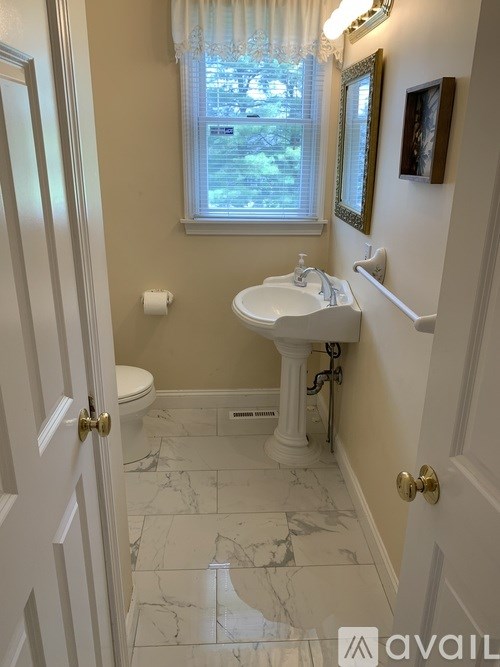 A bathroom with a toilet, sink and window.