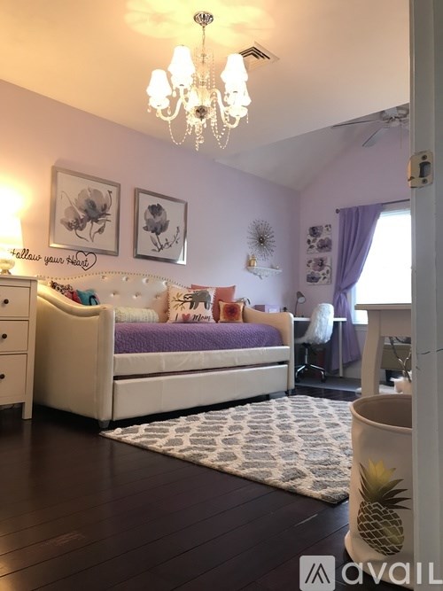 A bedroom with a bed, dresser, and chandelier.