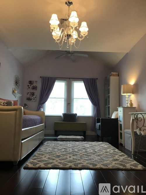 A bedroom with a chandelier, a bed, a bench, and a dresser.