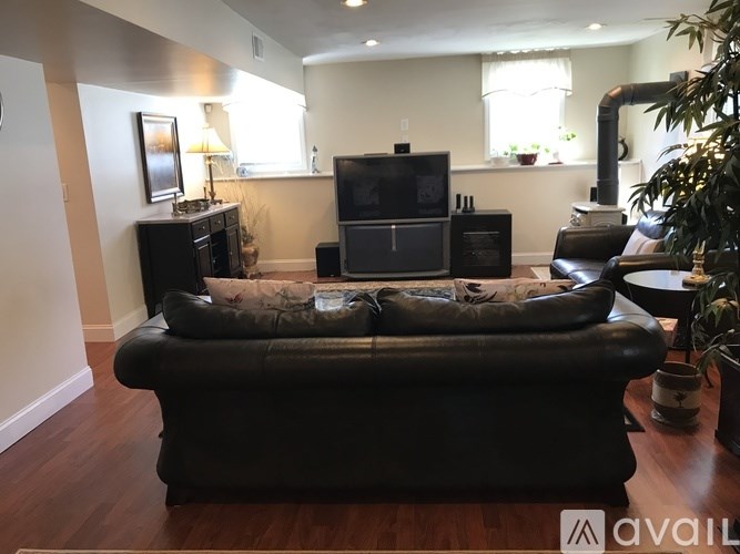 A living room with a black leather couch and a television.