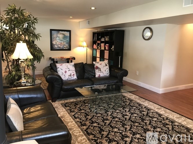A living room with a black couch and a glass coffee table.