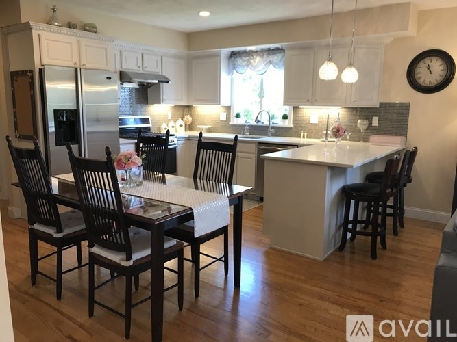 A kitchen with a table and chairs in the foreground and a refrigerator in the background.